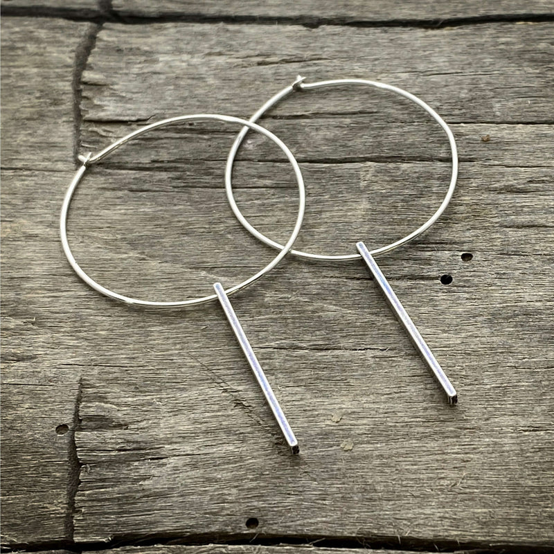 Twigs Hoop Earrings in Matte Silver on a rustic wooden background, showcasing a stylish clean design.