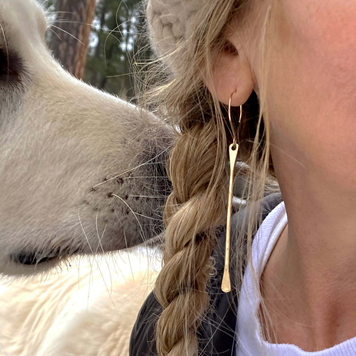 Close-up of Upstream Paddle Earrings worn by a woman next to a friendly dog, showcasing their stylish design.