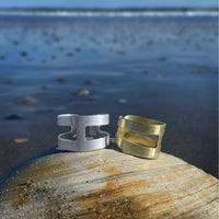 Wide Open Adjustable Ring in Matte Silver and Antique Brass on a beach backdrop.