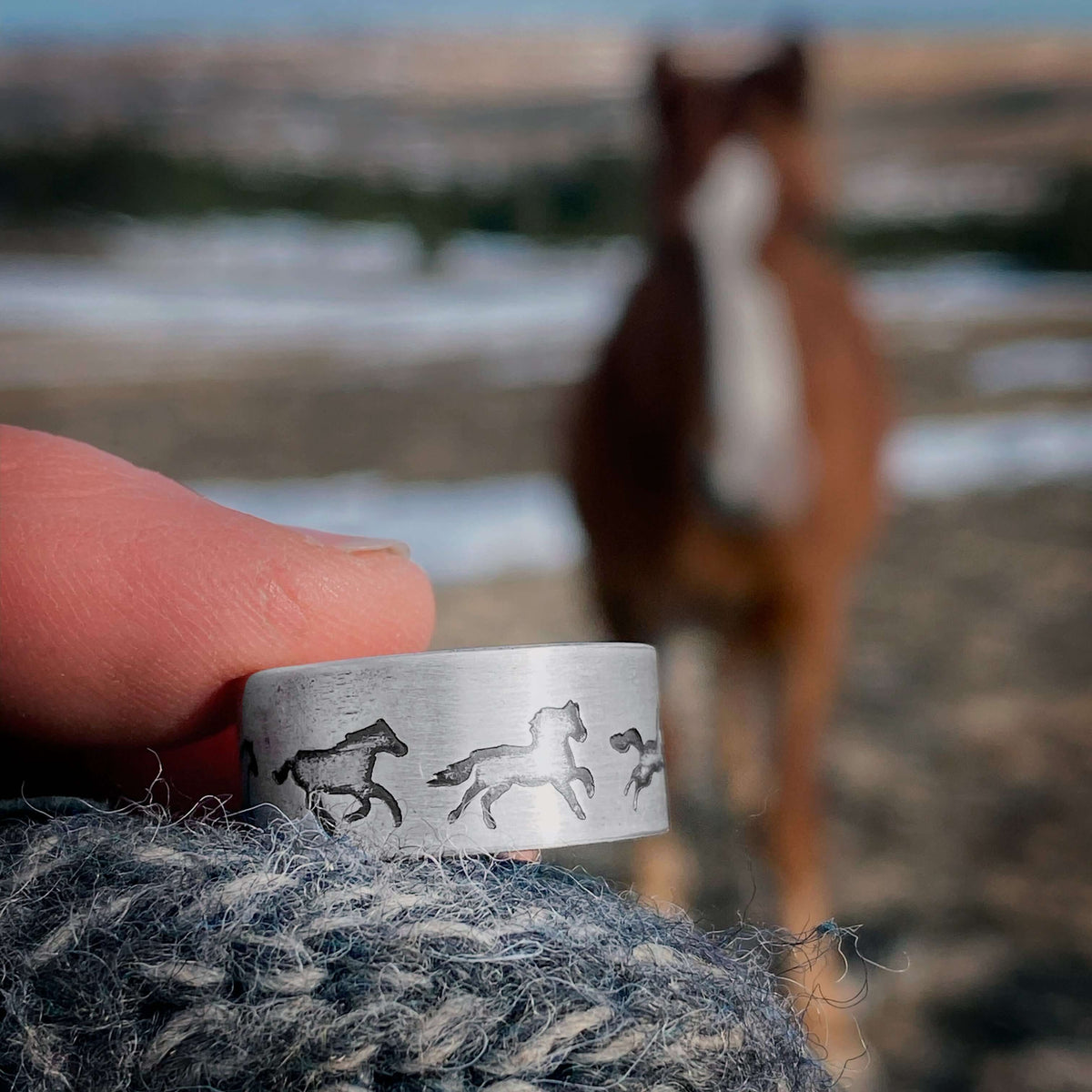 Wild Horses Adjustable Ring held in hand with galloping horses design, blurred horse background.